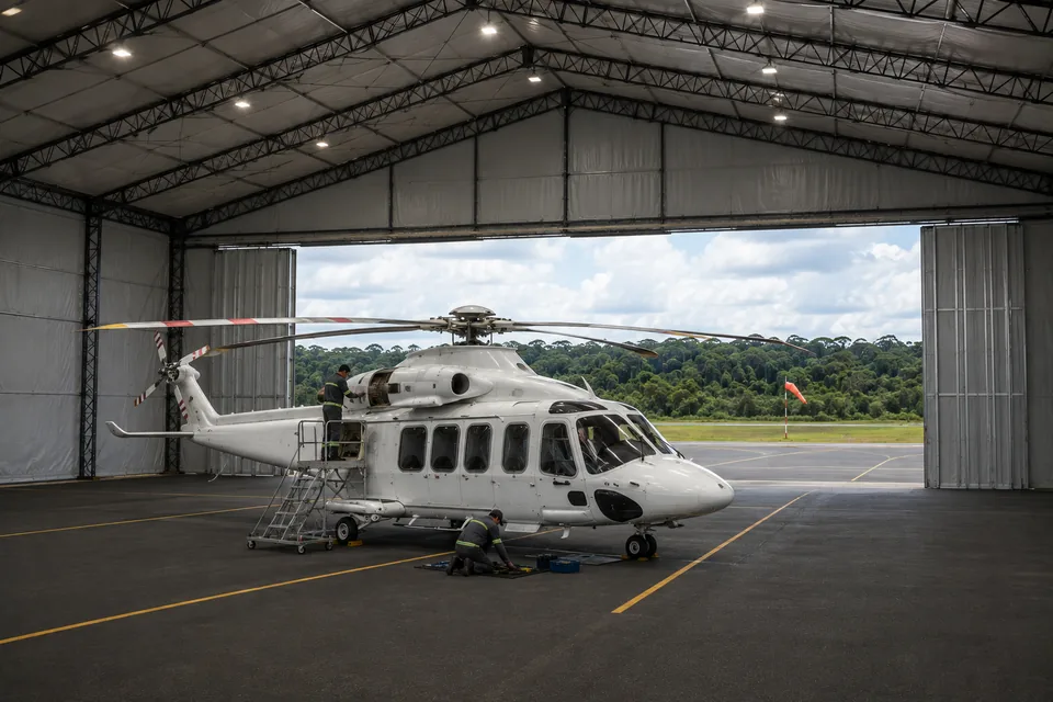 Interior do hangar lonado com helicóptero abrigado e a testeira aberta para a pista