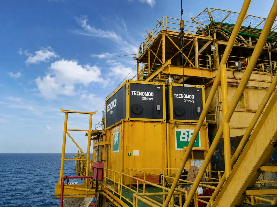 Módulos offshore Tecnomod instalados sobre containers em plataforma marítima, vistos de fora com o mar ao fundo
