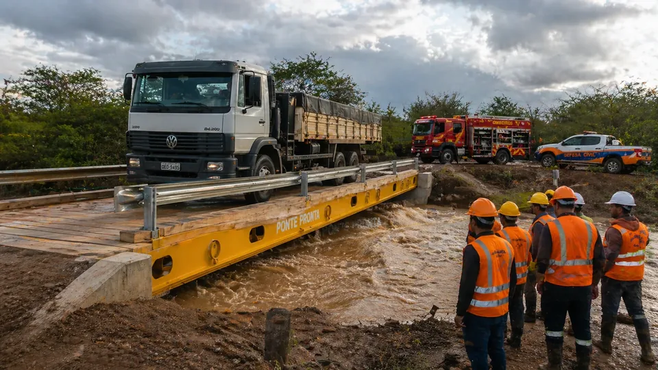 Equipe e viaturas junto à ponte modular Ponte Pronta instalada sobre rio cheio, com o acesso já liberado
