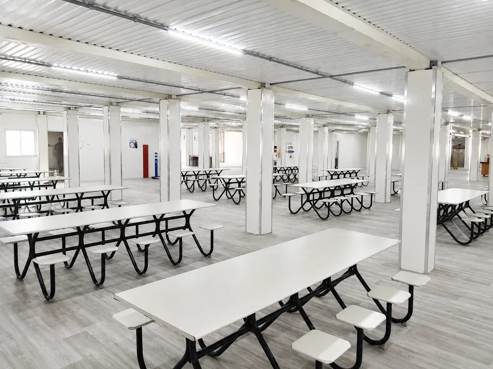 Refeitório modular com mesas coletivas de assento fixo, extintor e sinalização de emergência